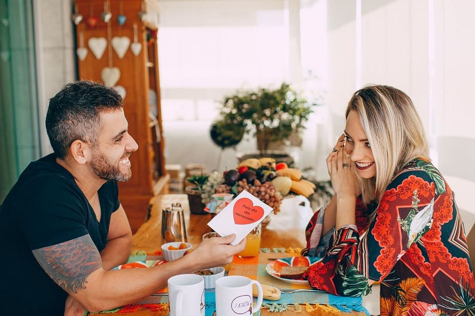 Happy couple having a playful breakfast at home, sharing a loving moment.
