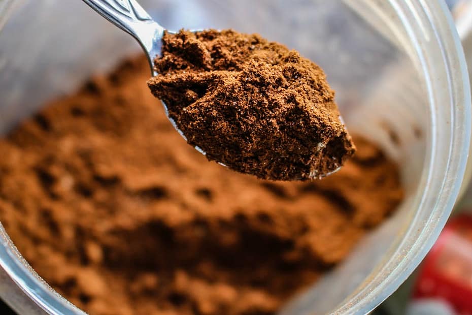 Focused shot of a spoon scooping cocoa powder from a container, emphasizing texture.