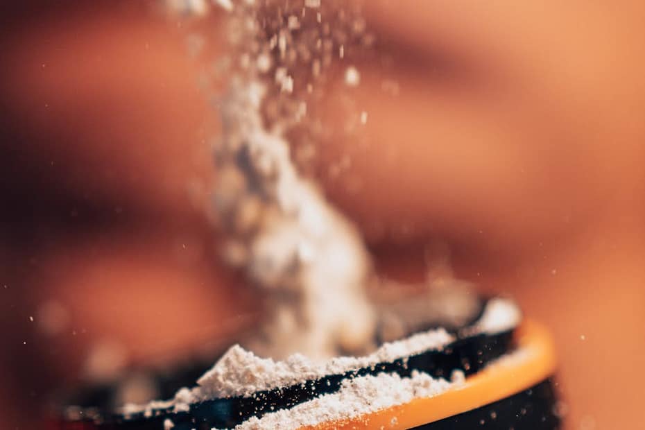 Dynamic shot of protein powder being added to a shaker, fitness concept.