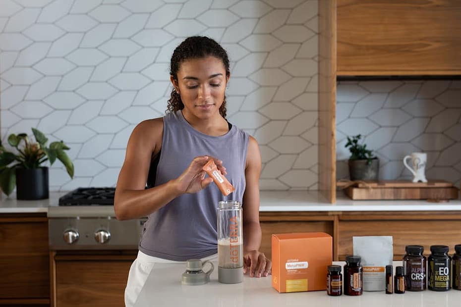 A woman uses essential oils and supplements in a contemporary kitchen for wellness.