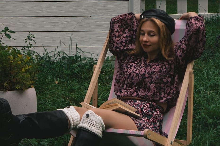 A woman in a floral dress lounges in a garden chair, exuding a relaxed vibe.