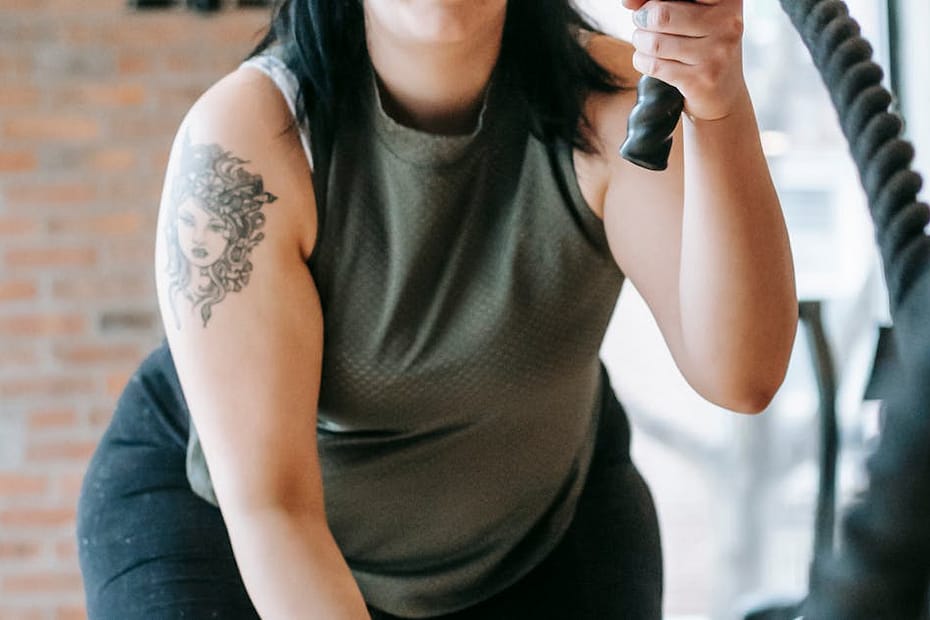 Low angle of concentrated female in sportswear exercising with heavy battle ropes during intense functional training