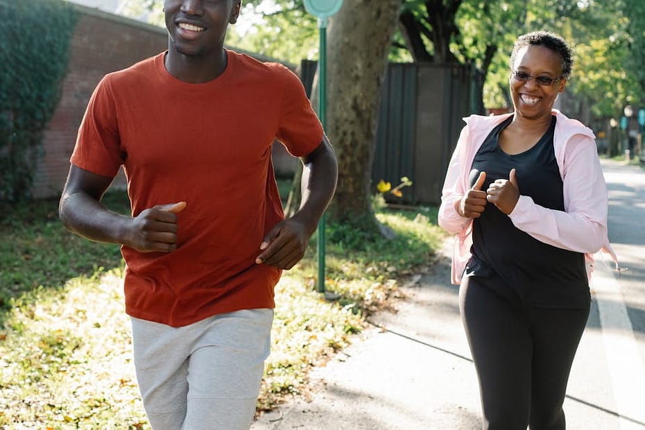Happy couple enjoys jogging in a sunny park, embracing a healthy lifestyle.