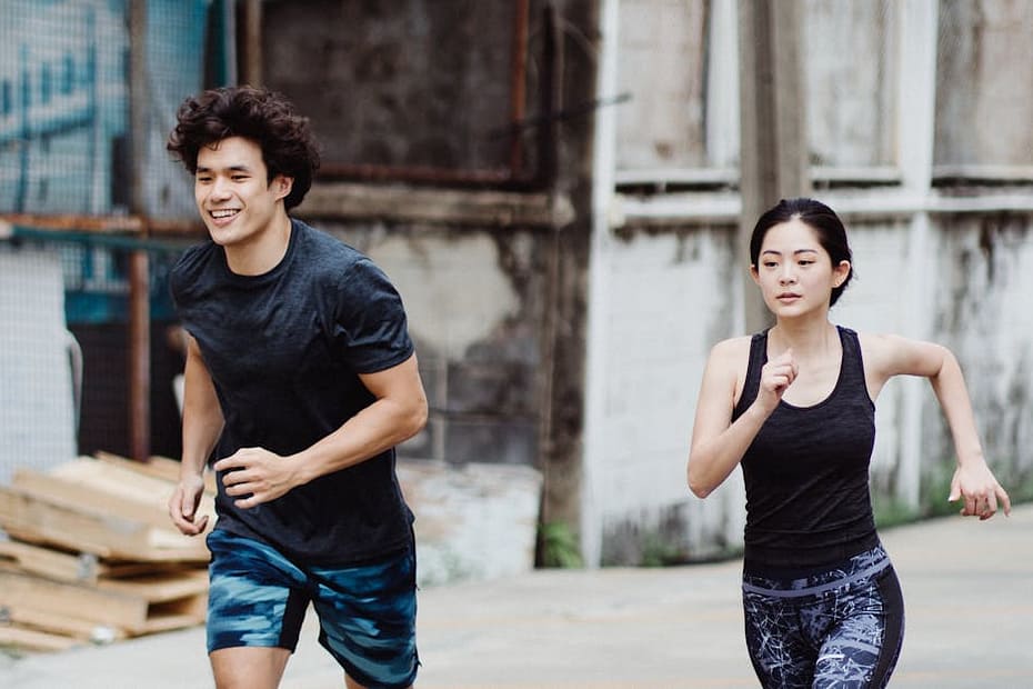 A couple in athletic wear jogging together in an urban environment, promoting fitness and outdoor activity.