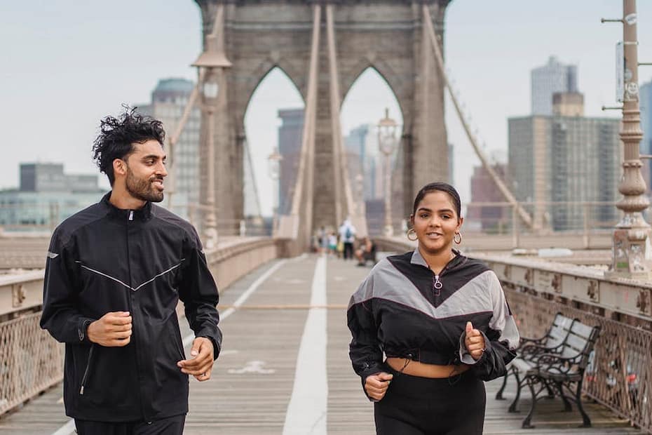 A man and woman jogging together on the iconic Brooklyn Bridge in New York City.