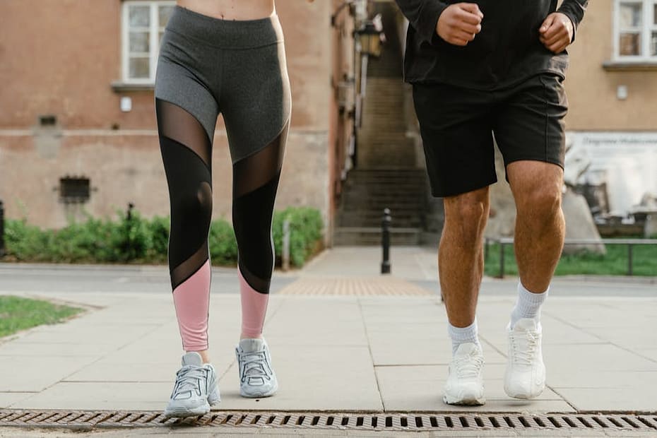 Two adults jogging outdoors, promoting health and fitness in an urban setting.