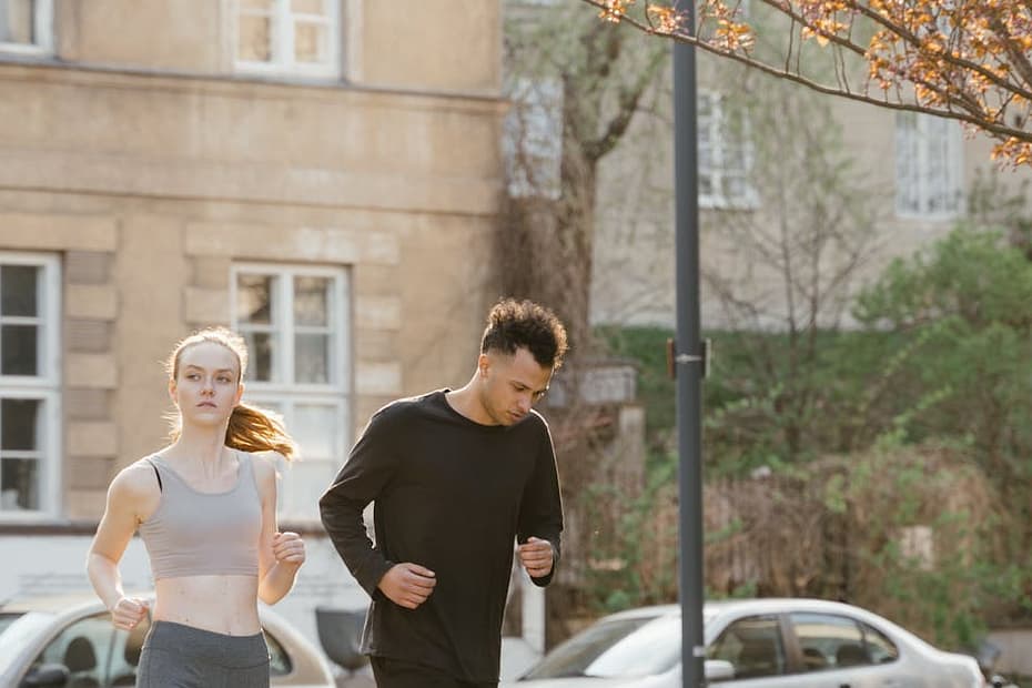 Young couple enjoys a jog outdoors in a sunlit park setting during spring.